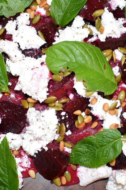 Roasted beetroot with goat's cheese, toasted seeds and fresh basil, close up