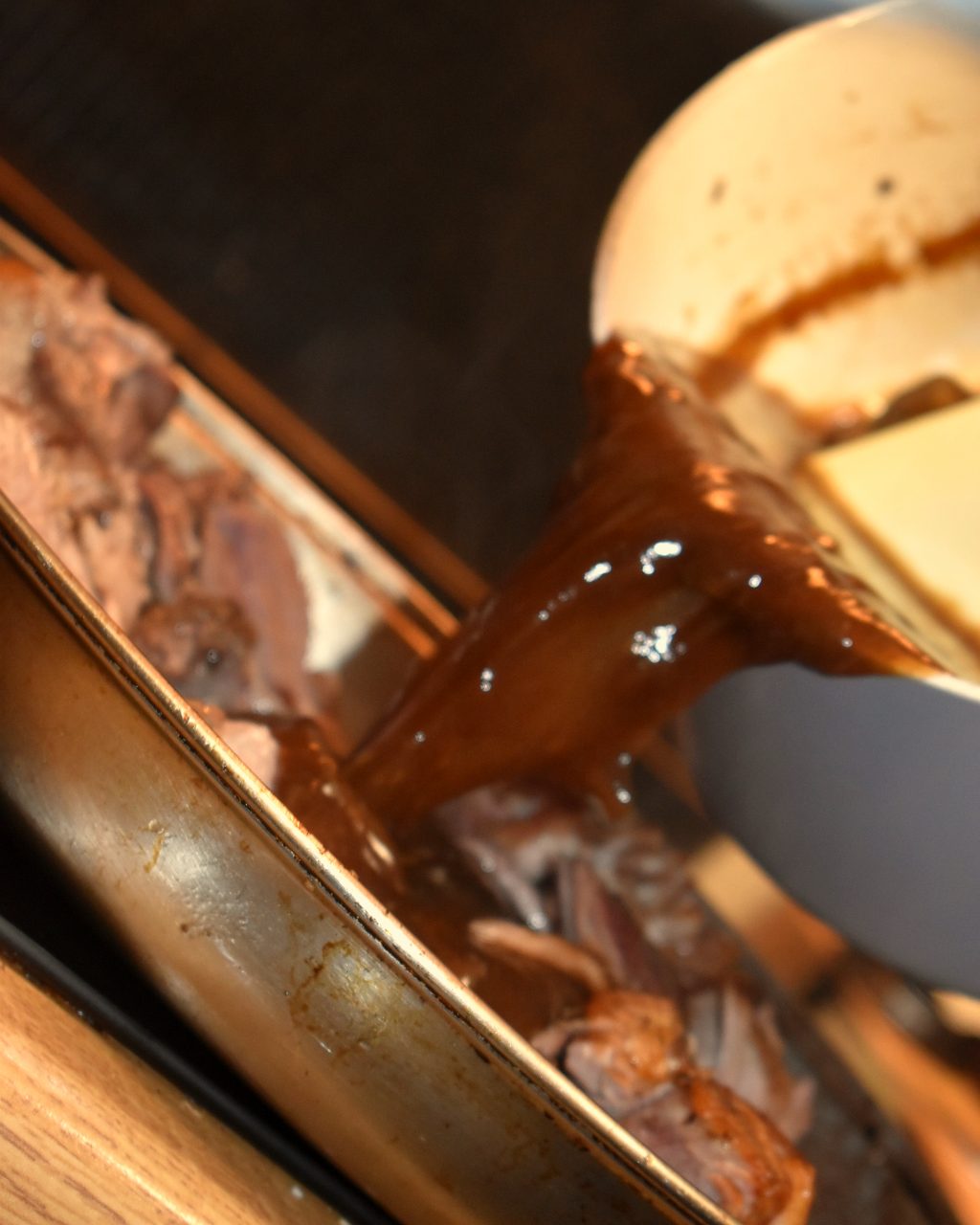 Rich gravy being poured over slow-cooked meat in the Light & Salt kitchen