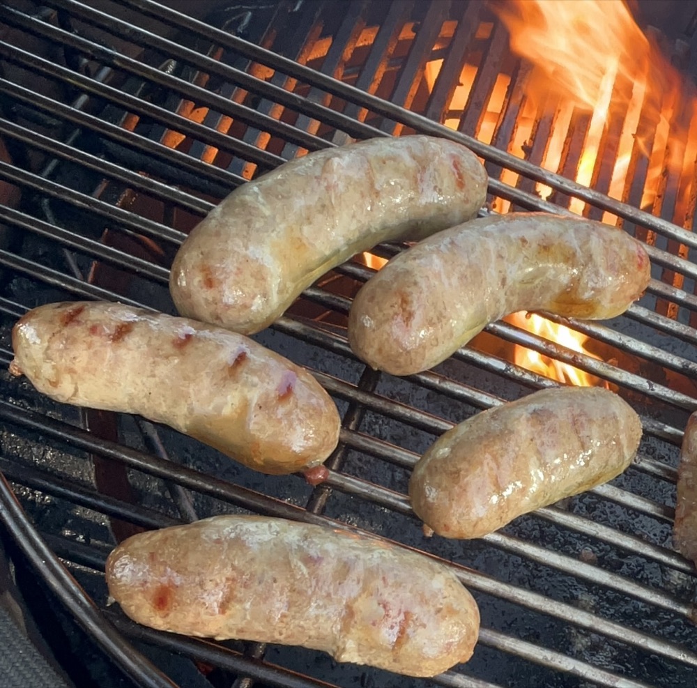 Sausages cooking over fire on the kamado grill at Light & Salt Provisions.